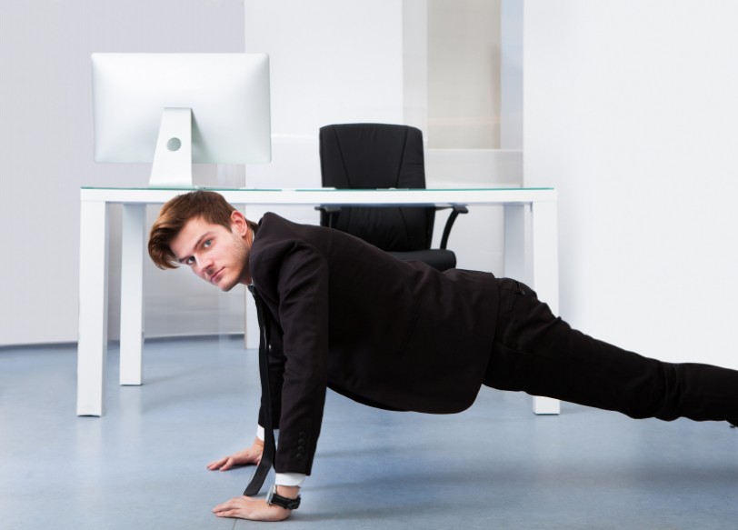 Young Businessman Doing Pushups At His Workplace